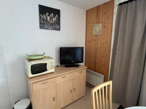 eine Mikrowelle auf einem Holzschrank mit einem Fernseher in der Unterkunft Appartement Sud avec Terrasse et Garage à Super Besse - FR-1-814-96 in Besse-et-Saint-Anastaise