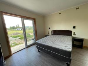 una camera da letto con un letto e una grande finestra di ApartHotel Cuatro Estaciones Frutillar Bajo a Frutillar