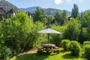 a picnic table with an umbrella in the grass at Mountainside Inn 309 by Alpine Lodging Telluride in Telluride +1 photo