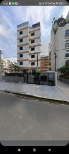 una calle de la ciudad con un edificio alto en el fondo en Apê na Enseada - Ar, Wi-Fi, garagem e praia a pé!, en Guarujá