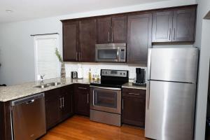 a kitchen with wooden cabinets and stainless steel appliances at Fire Pit - 4 Min from UNC - 7 Min from Carrboro - Fast Wi-Fi in Chapel Hill