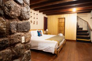 sypialnia z łóżkiem i kamienną ścianą w obiekcie Casa Amará w Cuzco