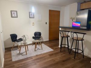 a kitchen with three chairs and a counter with a table at DPTO frente MALL-AEROPUERTO, CONCEPCION in Concepción
