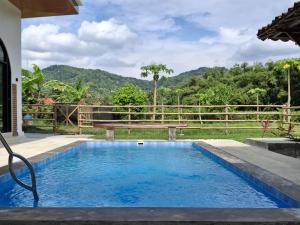 a swimming pool in a backyard with a wooden fence at Sri Gaïa Yogyakarta in Imogiri