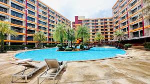 een zwembad met 2 stoelen en een gebouw bij Cozy condo maikhao Phuket in Ban Mai Salae