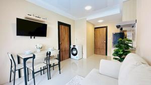 een woonkamer met een eettafel en een tv bij Cozy condo maikhao Phuket in Ban Mai Salae