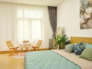 a bedroom with a bed and a table with chairs at VIlLA LÀ LÁ HOMESTAY VINHOMES GRAND PARK in Gò Công +41 photos