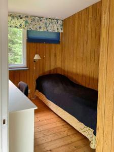 a bedroom with a black bed with a window at Forest Cottage Near The Sea On Orust in Henån