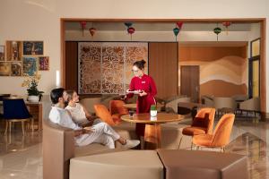 a woman standing in a room with two people sitting around a table at Hoi An Royal Beachfront Villas in Dien Ban +118 photos
