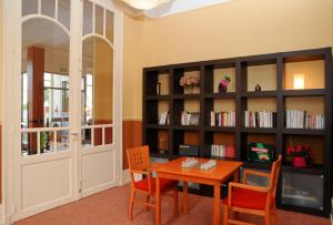 une salle à manger avec une table et une étagère à livres dans l'établissement Hotels & Résidences - Les Thermes, à Luxeuil-les-Bains