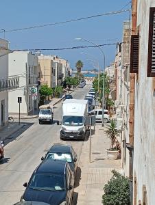 una strada cittadina con auto parcheggiate e un camion di In riva al mare 51 a San Vito lo Capo