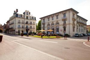 an empty street with buildings and tables and umbrellas at Hotels & Résidences - Les Thermes in Luxeuil-les-Bains