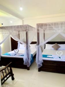a bedroom with two beds with mosquito nets at SILVER RAIL in Galle