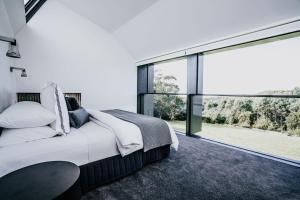 a bedroom with a bed and a large window at Alkina Lodge Milu in Wattle Hill +24 photos