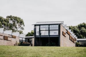 a brick house with large windows on a grass field at Alkina Lodge Milu in Wattle Hill