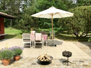 a patio with a table and an umbrella and a grill at Lovely Summerhouse By Sejerø Bay in Vig