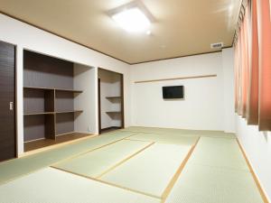 an empty room with a door and a room with shelves at Onsenminshuku Kosakaya in Katsuura