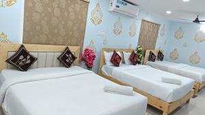 a room with three beds with white sheets at SRI NILAYAM Inn in Tirupati