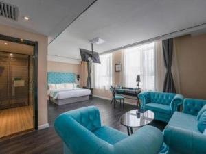 a large living room with blue furniture and a bed at Xana Hotelle Ulanqab Municipal Government Wanda Plaza in Jining