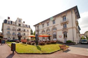 un gran edificio con un parque enfrente en Hotels & Résidences - Le Metropole en Luxeuil-les-Bains