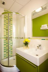a bathroom with a sink and a glass shower at Hotels & Résidences - Le Metropole in Luxeuil-les-Bains
