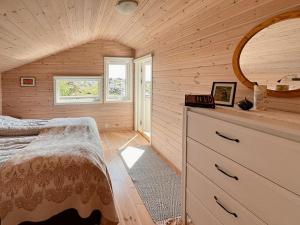 a bedroom with a bed and a dresser with a mirror at Traditional Cabin With Sea View In Jæren in Sirevåg
