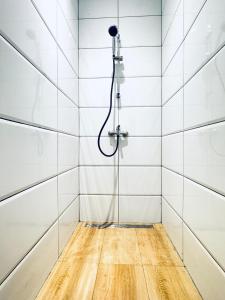 a shower in a white tiled bathroom with a wooden floor at Elegant 5-BR shared Home , Ideal for Groups & Families in Vienna