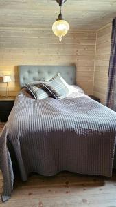 a bed in a bedroom with a wooden wall at New Cabin With Panoramic Views Of Lake Osen in Hektner