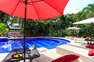 a red umbrella sitting next to a swimming pool at Apartments at Pajaro de fuego Sayulita in Sayulita
