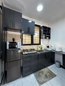 una cocina con armarios negros y electrodomésticos de acero inoxidable en BnV homes, en Dar es Salaam