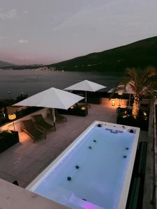 KravljaPenthouse Apartment mit Meerblick in der Bucht von Kotor mit Pool Area- 400m bis zum Strand的庭院内一个带桌子和遮阳伞的游泳池