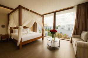 a bedroom with a canopy bed and a table with a vase of flowers at Ducat Living in Canggu +33 photos