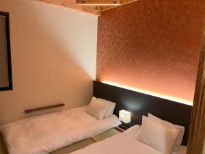a small room with two beds with white pillows at おおさか城北 宿福 in Osaka