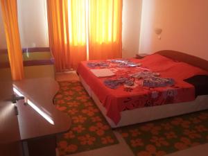 een slaapkamer met een bed met een rood dekbed bij Apartments in Villa Rouge in Sozopol