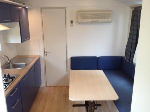 a small kitchen with a blue couch and a table at Oliholiday Mobilehomes - Cavallino in Cavallino-Treporti