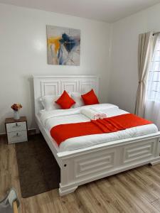 ナイロビにあるRestful Escape- 2br with Pool TatuCityの白いベッド(赤い枕付)が備わるベッドルームです。