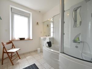 a white bathroom with a shower and a tub and a chair at Home for 7 Guests in Plouvara in Saint-Donan