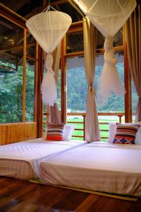 a bedroom with two beds with curtains and a window at Chải Eco Home in Mù Cang Chải