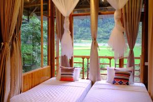 two beds in a room with a large window at Chải Eco Home in Mù Cang Chải