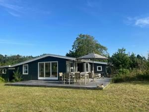 a blue house with a deck and a table and chairs at Holiday Home With Panoramic View Of Kalø Bay in Knebel