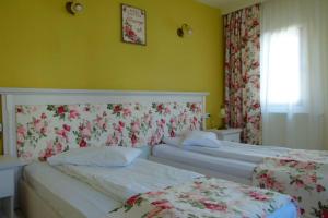 2 camas en un dormitorio con flores en la pared en Pensiunea Cabana Soimul, en Comăneşti