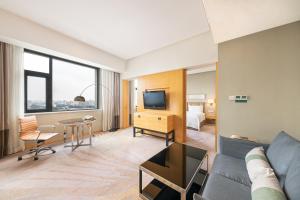 a living room with a couch and a tv and a bed at Holiday Inn Beijing Deshengmen by IHG on 2nd Ring Road Extension 10-15 minute taxi ride to Shichahai Lama Temple Drum Tower Close to Beijing North Station for Badaling Great Wall Near Exit B Jishuitan Metro Line 2 in Beijing