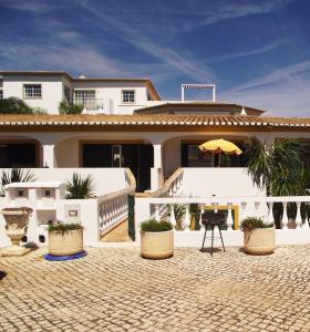 a white house with a patio and an umbrella at Casas da Vila in Luz