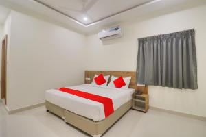 Un dormitorio con una cama con almohadas rojas. en Hotel O Kakatiya Residency, en Warangal