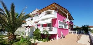 a pink and white building with a palm tree at Nereids Apartments and Studios in Chrysi Ammoudia