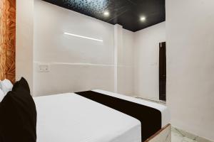 Dormitorio blanco con cama blanca y cabecero negro en Hotel O The Signature Stay, en Nueva Delhi