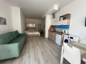 a living room with a green couch and a kitchen at SEA Apartment Maria Balchik in Balchik +7 photos