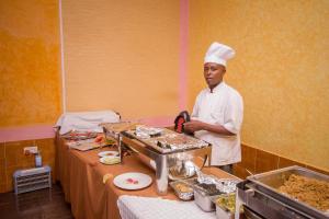 un chef de pie en una cocina preparando comida en Grande Hotel en Isiolo