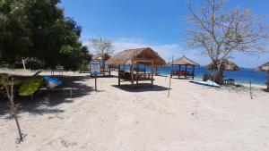 a beach with chairs and straw umbrellas and the ocean at Madak ekas homestay 2 in Ekas