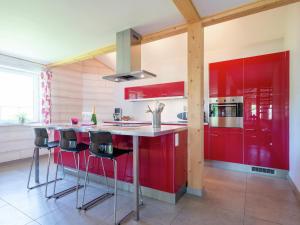 a red kitchen with red cabinets and bar stools at Rustic Retreat, Ovifat in Waimes